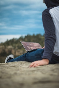 Person sitting outside working on their laptop